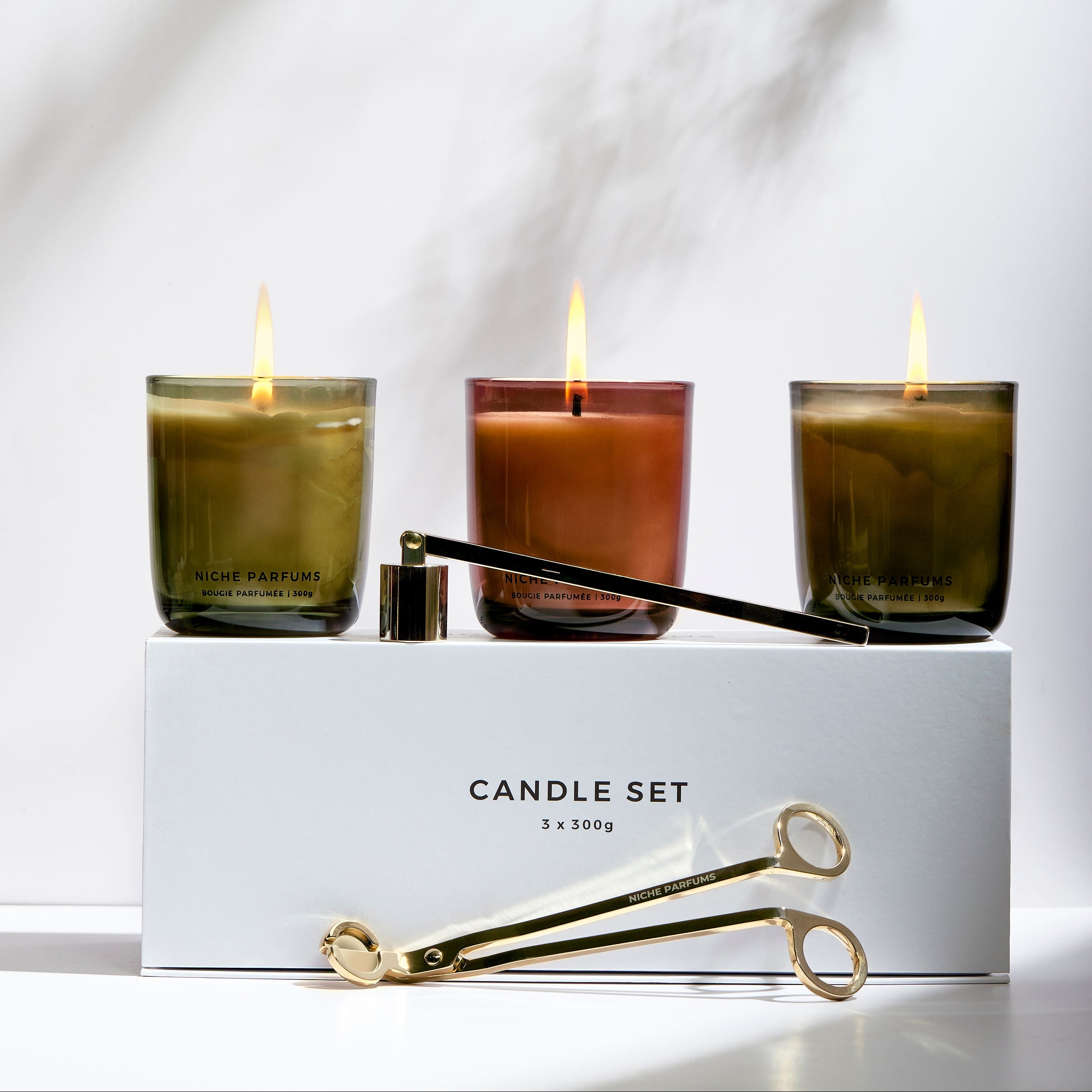 Set of three candles in glass containers with a white box labeled 'Candle Set' on a light background.